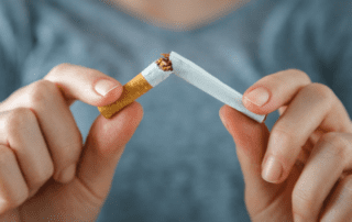 a close up of a person's hands breaking a cigarette