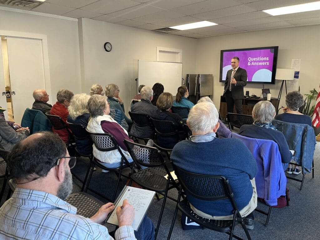 An audience watching a man in a suit speaking.
