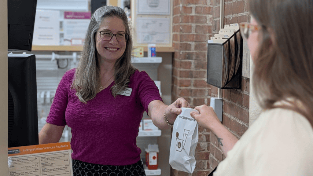 Pharmacist hands a bag to a patient
