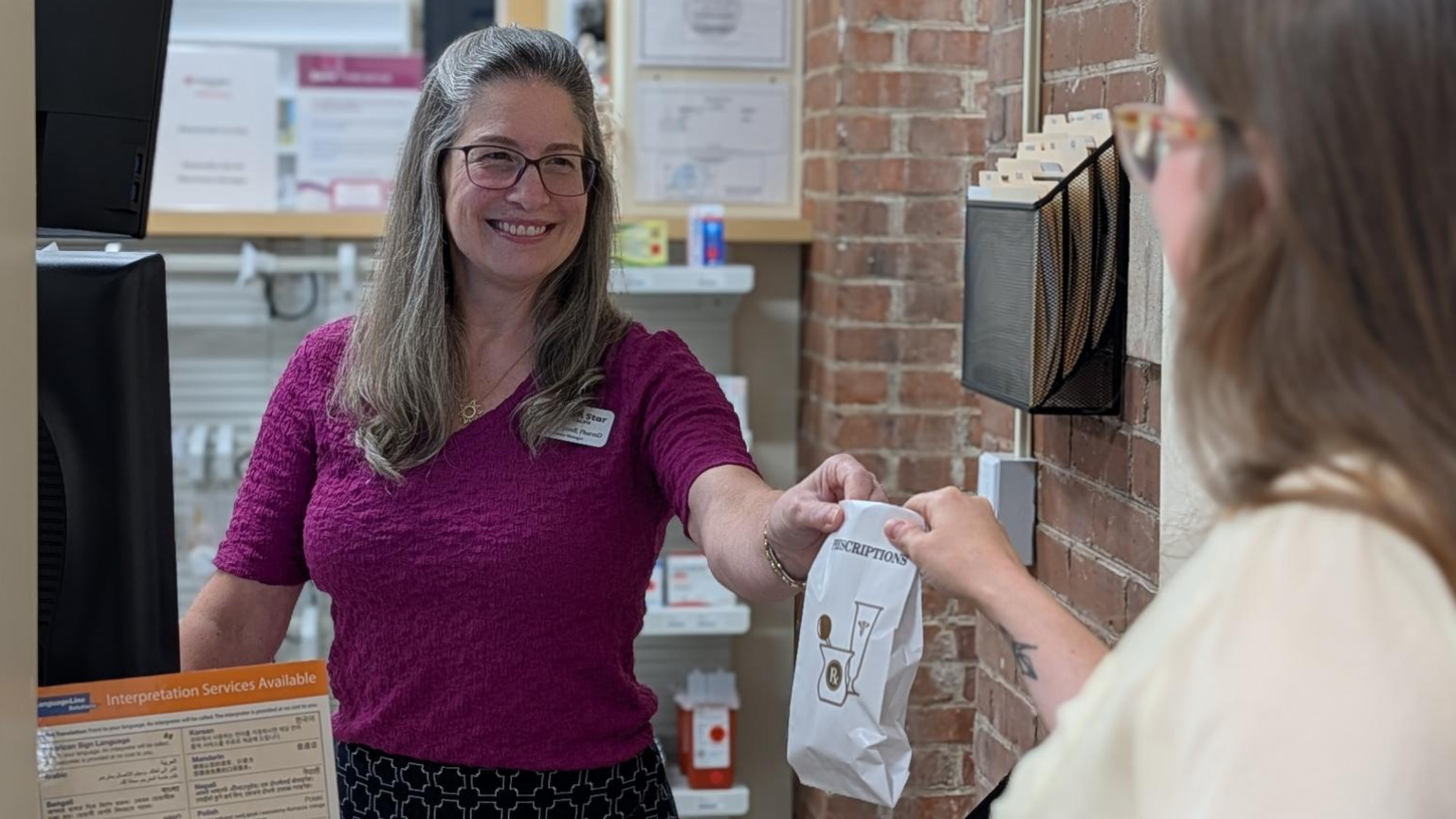 Pharmacist hands a bag to a patient